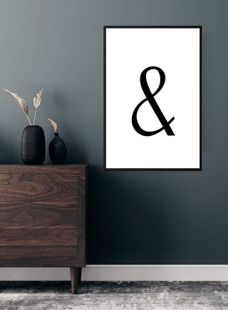 Minimalist poster featuring a large black ampersand symbol on a white background, framed and hung above a dresser.
