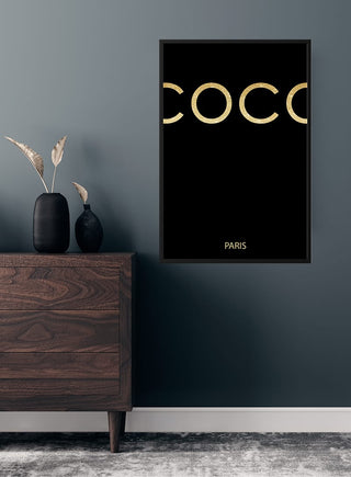 Black COCO poster with gold text "COCO" and "PARIS," displayed in a modern, minimalist room setting.