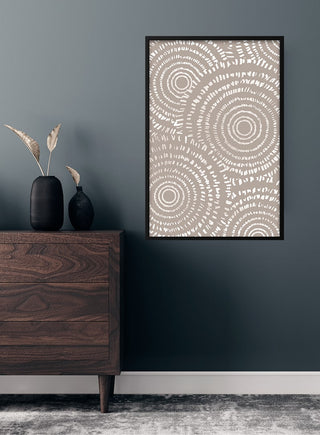 Art poster with brown circular patterns displayed on a dark wall above a wooden dresser in a modern living room.