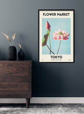 Framed Flower Market - Tokyo poster featuring a pink lotus on a blue background, displayed above a wooden dresser.