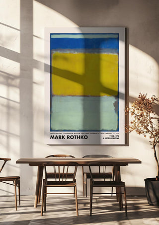Poster of Mark Rothko's "Blue Yellow Green" hangs above a wooden table and chairs in a sunlit room.