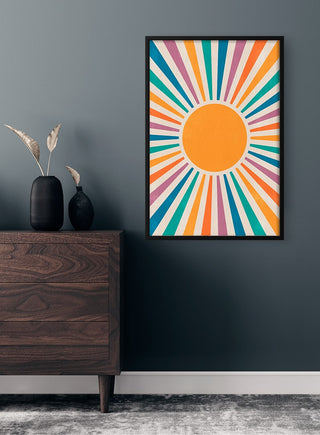 Framed Colorful Sun Plakat with vibrant rays, displayed above a dark wood dresser in a modern room.
