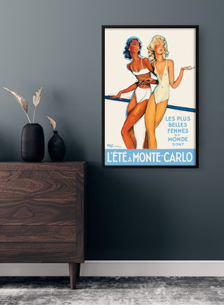 Framed Léte a Monte-Carlo Plakat featuring two women in swimsuits displayed above a wooden dresser.