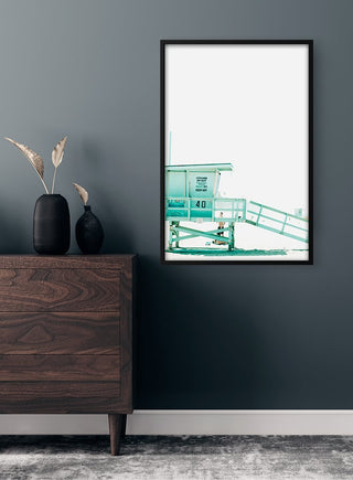 Framed Beach Tower Plakat on a dark wall above a wooden dresser with decorative vases.