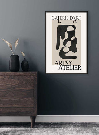 Abstract black shapes art poster titled "Galerie D'art" hanging on a dark wall above a wooden dresser.