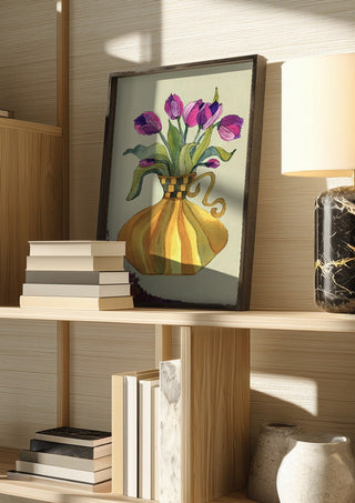Lilac tulips by Marjorie Salvagni in a dark frame on a wooden shelf beside books and a lamp