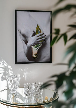 Duermen los volátiles by Rocio Montoya in a black frame above a glass table with crystal glassware