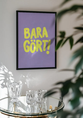 Bara gört! by Grafik bageri in a black frame above a glass table with crystal glassware