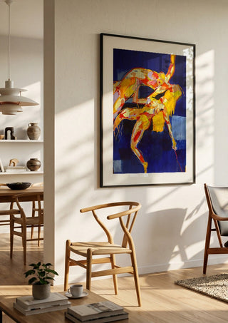 Two Figures in Blue by René J in a black frame in a bright dining room with wooden chairs