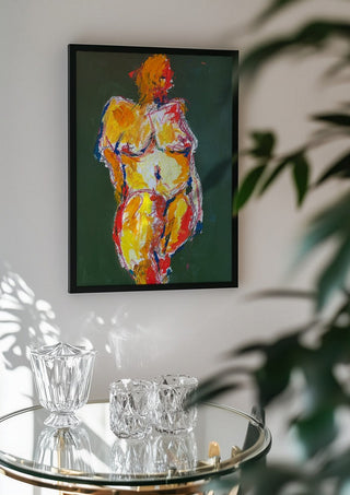 Standing Nude by René J in a black frame above a glass table with crystal glassware