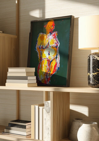 Standing Nude by René J in a dark frame on a wooden shelf beside books and a lamp
