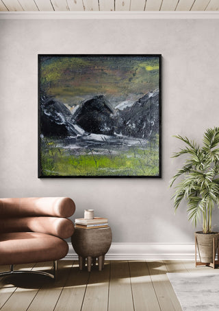 Dark Hills by luco art in a black frame above a tan leather chair beside a potted plant
