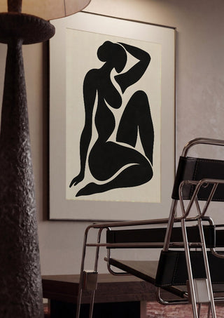 Black Nude Silhouette – Minimalist Abstract Figure Wall Art by TimlessArtworks framed in a dim room beside a tubular steel chair