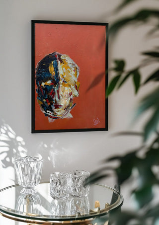 Head in Colour by René J in a black frame above a glass table with crystal glassware