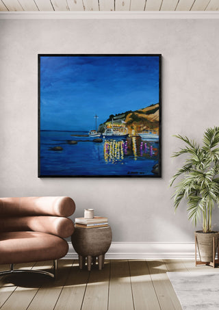 Evening Boats by Nella Hajdu in a black frame above a tan leather chair beside a potted plant