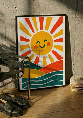 Smiling Sun by Decker Studios in a black frame leaning against a concrete wall by a steel chair