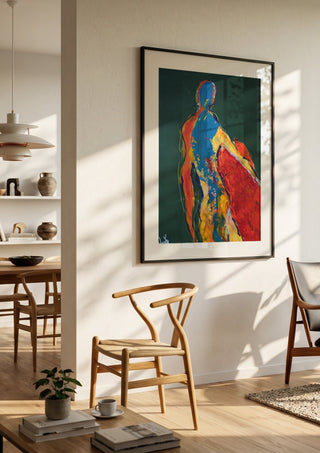 Figure in Green by René J in a black frame in a bright dining room with wooden chairs