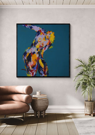Leaning Back by René J in a black frame above a tan leather chair beside a potted plant