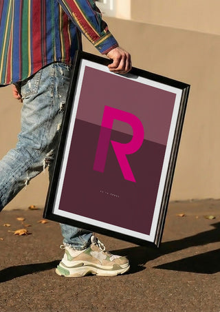 R as in Rebel – Cerise by Quite Nice Prints carried in a black frame along a sunny street