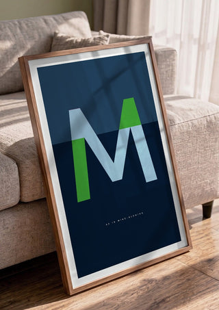 M as in Mind-blowing – Blue by Quite Nice Prints in a walnut frame leaning against a grey sofa