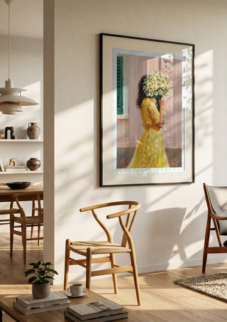 Girl in yellow dress with flowers by Ohkimiko in a black frame in a bright dining room with wooden chairs
