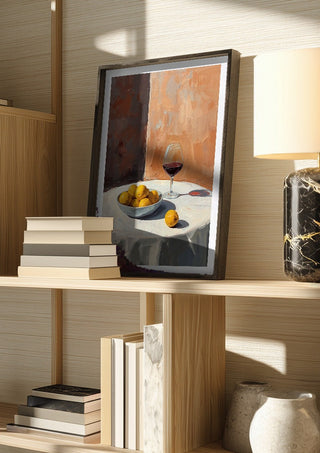 Summer scene: Lemons and wine by Ohkimiko in a dark frame on a wooden shelf beside books and a lamp
