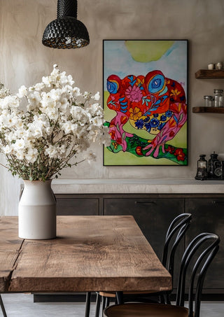 Color frog by Nittaart in a black frame above a rustic table with white flowers