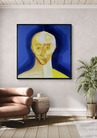 Ochre portrait / blue field by Linor Citaku in a black frame above a leather armchair beside a palm