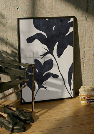 Shadowed Blooms by ThingDesign in a black frame leaning against a concrete wall by a steel chair