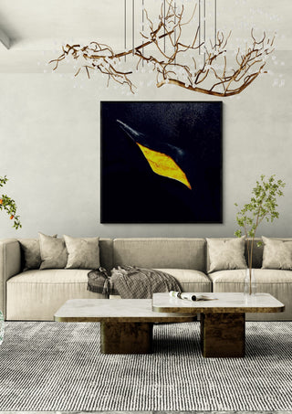 The golden crack by Marcel Herrmann in a black frame above a cream sofa under a branch chandelier