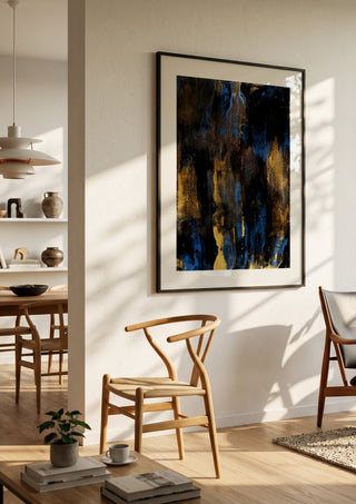 Gold on Blue by Kristof ellertz in a black frame in a bright dining room with wooden chairs