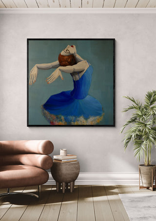 Ballerina in Blue by Justyna Kopania in a black frame above a leather armchair beside a palm
