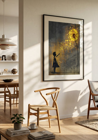 Golden Dandeloin x Banksy by Decker Studios in a black frame in a bright dining room with wooden chairs