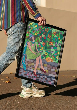 The Garden Wall by Camilla Nilsson carried in a black frame along a sunny street