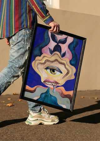 The Weeping Eye by Shimmering Ugly carried in a black frame along a sunny street