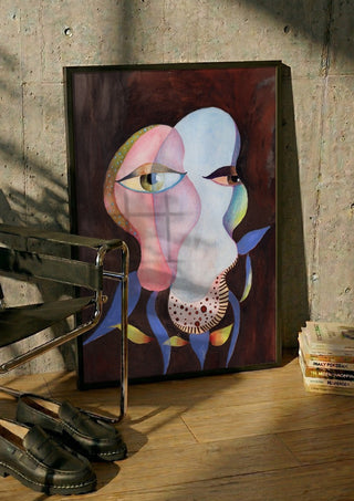 Two Eyes, One Head by Shimmering Ugly in a black frame leaning against a concrete wall by a steel chair