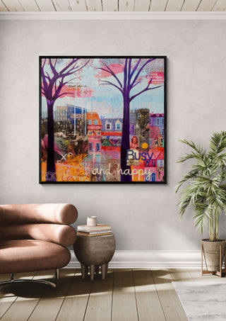 Busy and happy by María Burgaz in a black frame above a rose-pink armchair beside a palm