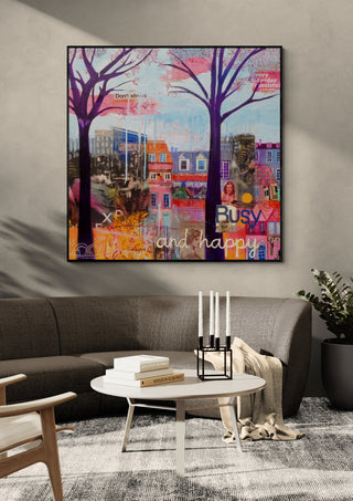 Busy and happy by María Burgaz in a black frame above a dark grey sofa with a candle holder