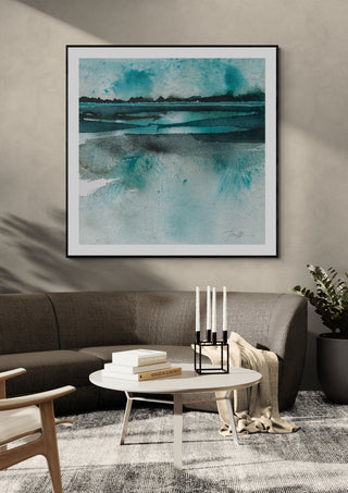 Reflections by Tania Zubareva in a black frame above a dark grey sofa with a candle holder