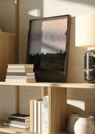 När älvorna dansar by Ljilja Marinic in a dark frame on a wooden shelf beside books and a lamp