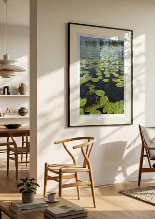 Sommarens sista andetag by Ljilja Marinic in a black frame in a bright dining room with wooden chairs