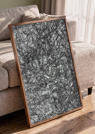Resized Imagination by Priit Ruttas in a walnut frame leaning against a grey sofa