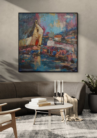 House by the Water by PaKart in a black frame above a grey sofa with a round table and candlesticks