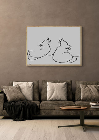 Two Cats by Eva Hartman in a pale wooden frame above a grey sofa with cushions