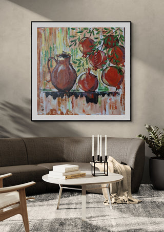 Pomegranates by Dina in a black frame above a grey sofa with candlesticks