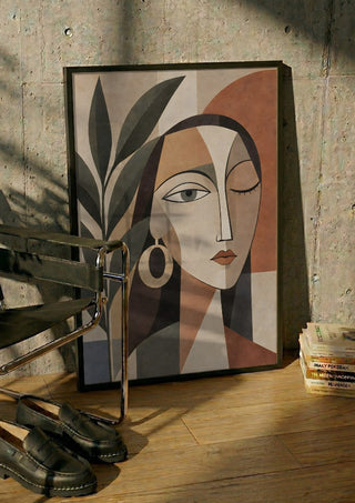 Cubist Woman Portrait with Plant by TimlessArtworks in a black frame leaning against a concrete wall by a steel chair
