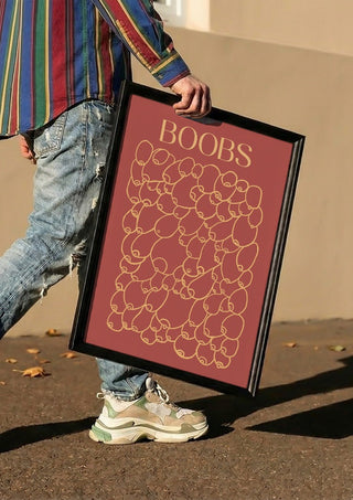 Boobs by Astrid Lind carried in a black frame along a sunny street