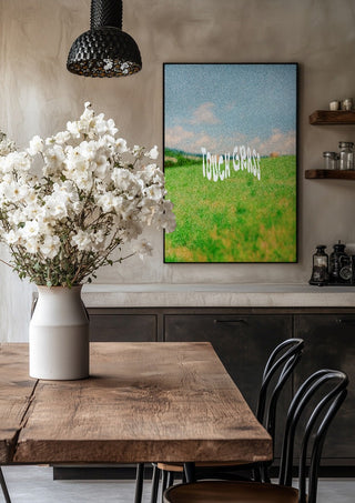 Touch Grass by Jakob Falkenberg in a black frame above a rustic table with white flowers