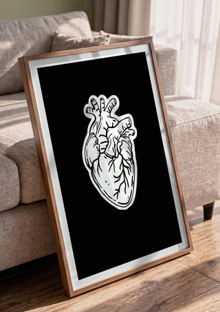 Still Beating by Nari in a walnut frame leaning against a grey sofa