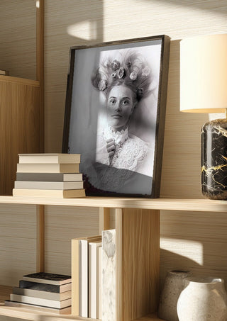 Klara by Bettinafloorphoto in a dark frame on a wooden shelf beside books and a lamp